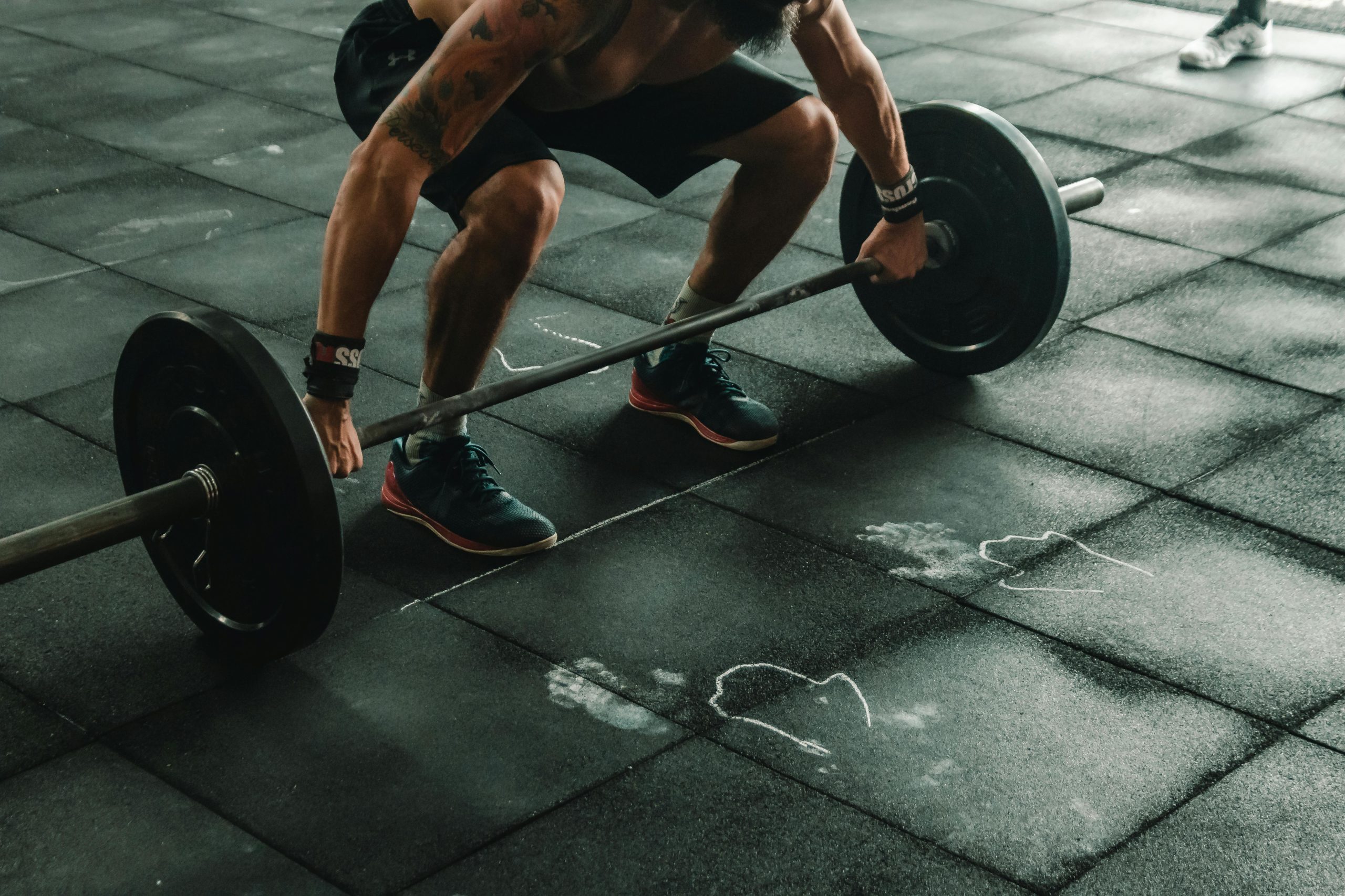 Man voert krachttraining uit met halters in een sportschoolomgeving